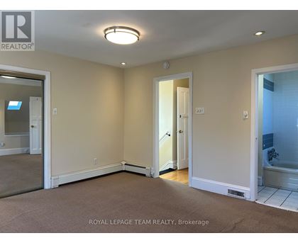A room with a carpet floor and a door leading to a bathroom.