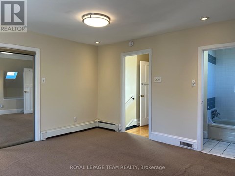 A room with a carpet floor and a door leading to a bathroom.