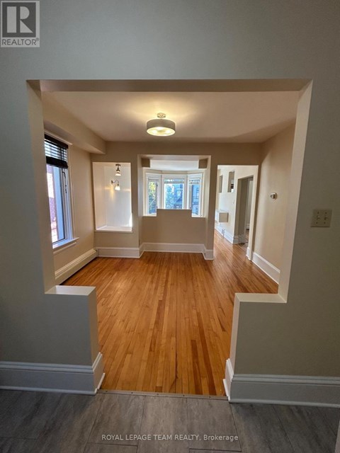 A well-lit, spacious room with wooden floors and white walls.