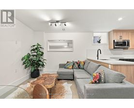 A modern living room with a grey couch, a wooden coffee table, and a large mirror on the wall.