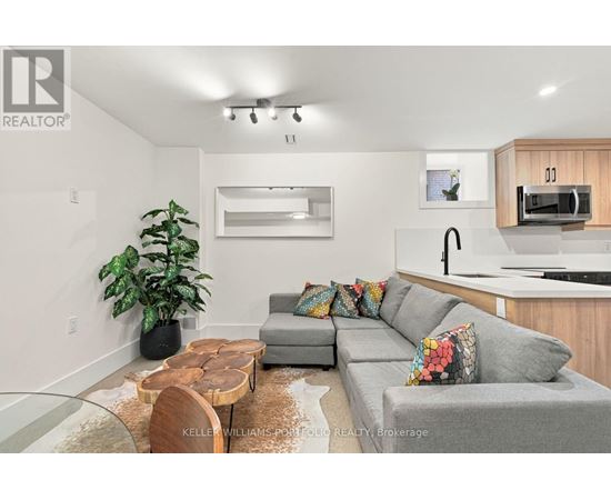 A modern living room with a grey couch, a wooden coffee table, and a large mirror on the wall.