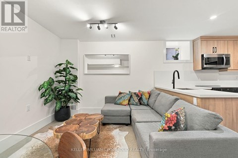 A modern living room with a grey couch, a wooden coffee table, and a large mirror on the wall.