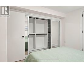 A white bedroom with a bed and a white door.