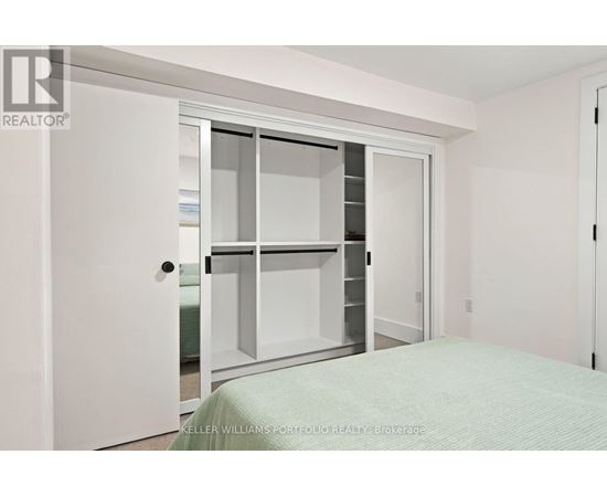 A white bedroom with a bed and a white door.