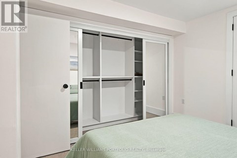 A white bedroom with a bed and a white door.
