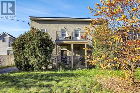 A house with a balcony is surrounded by trees and grass.