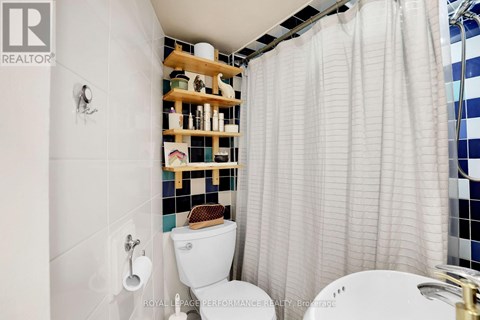 A white toilet with a wooden shelf above it.