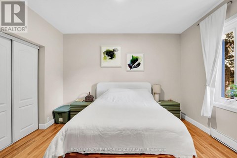 A bedroom with a white bed and two pictures on the wall.