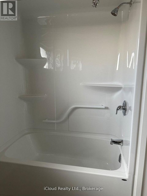 A white bathtub with a shower head and faucet.