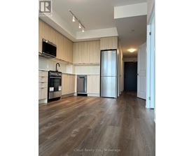 A kitchen with wooden floors and a black refrigerator.