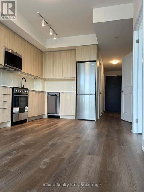 A kitchen with wooden floors and a black refrigerator.