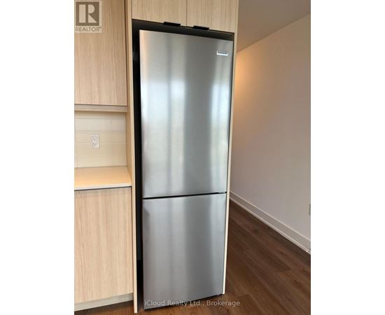 A stainless steel refrigerator in a kitchen with wooden cabinets.