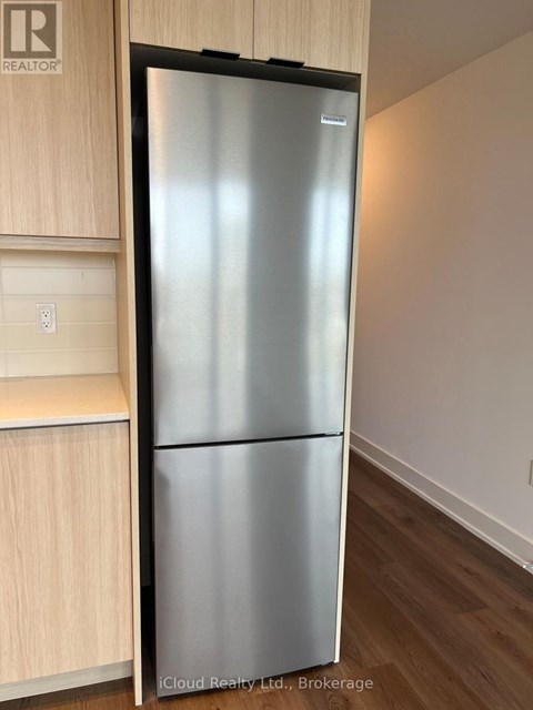 A stainless steel refrigerator in a kitchen with wooden cabinets.