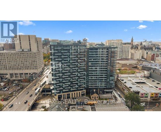 A tall building with many windows is in the middle of a city.