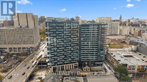 A tall building with many windows is in the middle of a city.