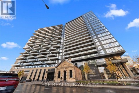A tall building with a glass facade stands next to a smaller, older structure.