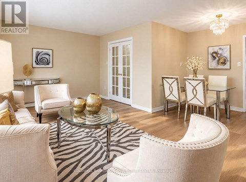 A living room with a glass coffee table and white chairs.