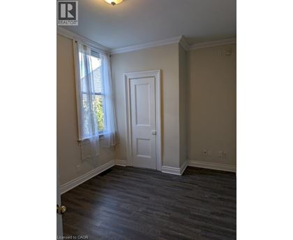 A room with a white door and a window with white curtains.