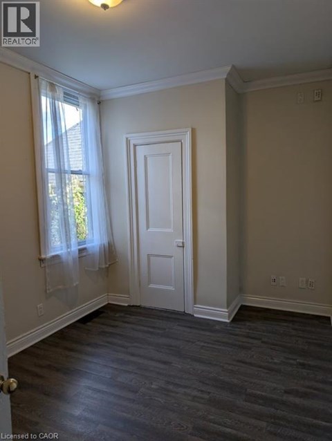 A room with a white door and a window with white curtains.