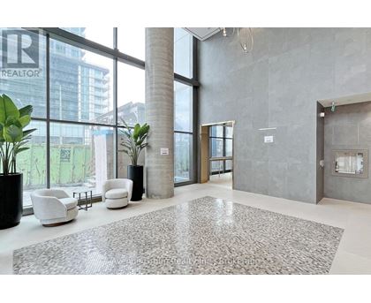 A large, modern office lobby with a grey carpet and white furniture.