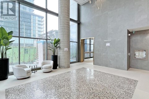 A large, modern office lobby with a grey carpet and white furniture.