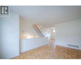 A spacious room with a staircase and wooden flooring.