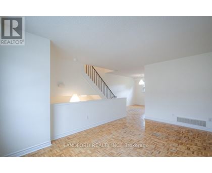 A spacious room with a staircase and wooden flooring.