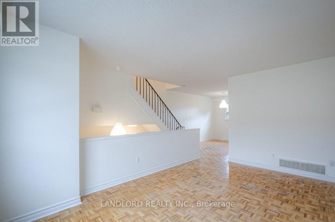 A spacious room with a staircase and wooden flooring.