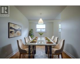 A dining room with a table set for six with a painting on the wall.