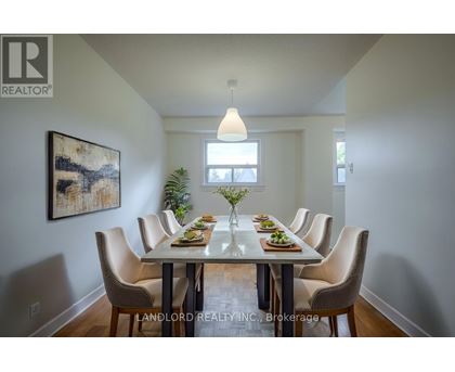 A dining room with a table set for six with a painting on the wall.