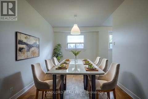 A dining room with a table set for six with a painting on the wall.