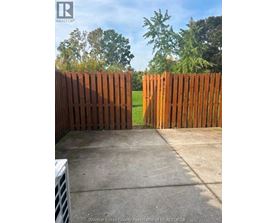 A brown wooden fence in front of a green field.