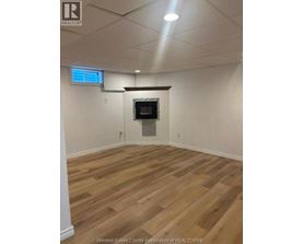 A room with wooden flooring and a flat screen TV mounted on the wall.