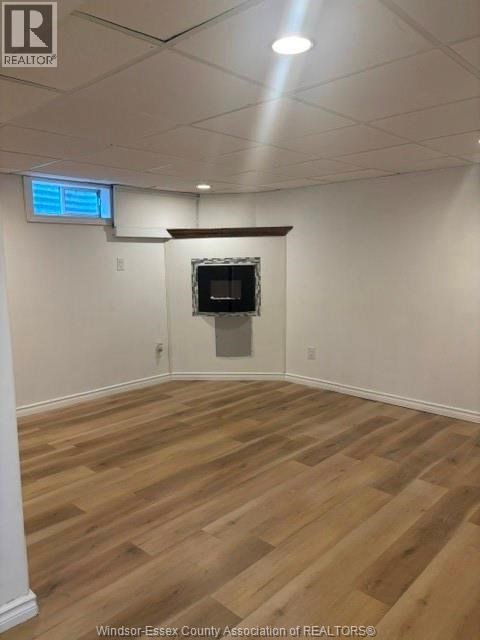 A room with wooden flooring and a flat screen TV mounted on the wall.