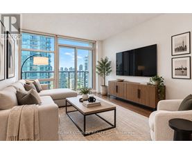 A living room with a large window, a couch, a coffee table, and a flat-screen TV.