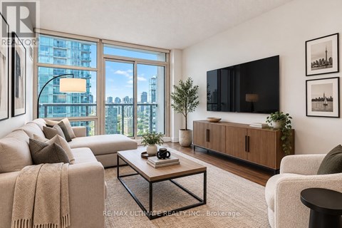 A living room with a large window, a couch, a coffee table, and a flat-screen TV.