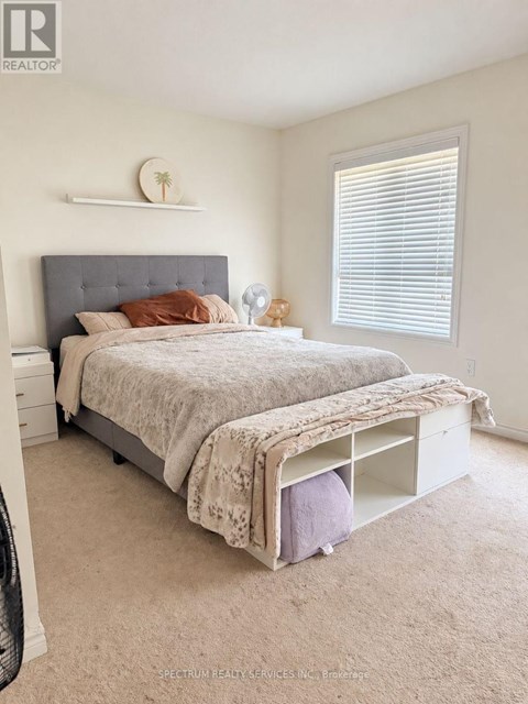 A bedroom with a bed, nightstand, and window.