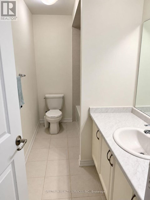 A white bathroom with a toilet, sink, and mirror.