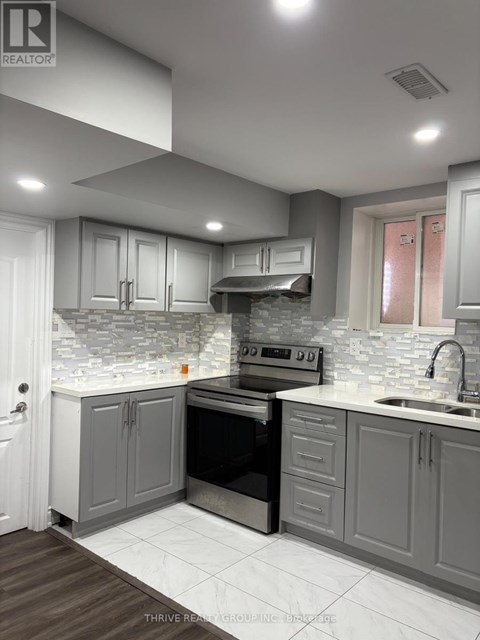 A modern kitchen with a stove top oven and a sink.