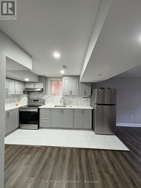 A modern kitchen with a refrigerator, sink, and oven.