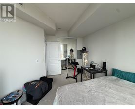 A bedroom with a bed, a desk with a chair, and a mirror on the wall.