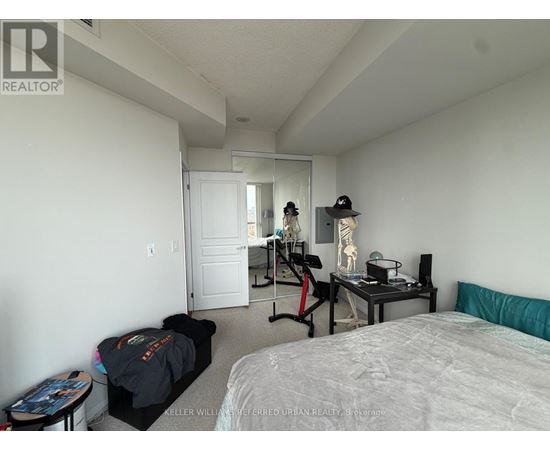 A bedroom with a bed, a desk with a chair, and a mirror on the wall.