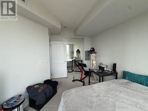 A bedroom with a bed, a desk with a chair, and a mirror on the wall.