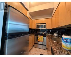 A kitchen with a stainless steel refrigerator and wooden cabinets.