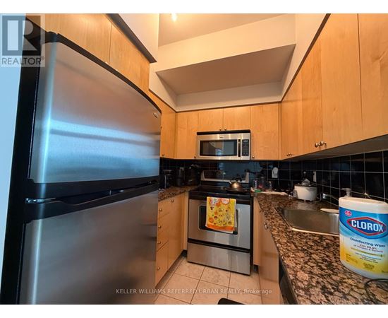 A kitchen with a stainless steel refrigerator and wooden cabinets.