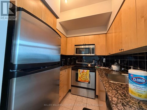 A kitchen with a stainless steel refrigerator and wooden cabinets.