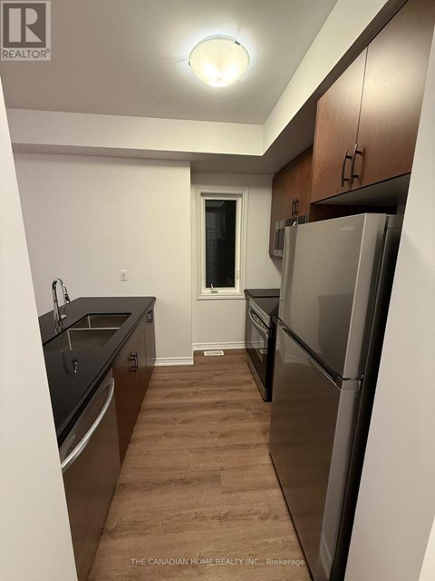 A kitchen with a refrigerator, sink, and cabinets.