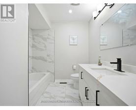 A white bathroom with a marble patterned tub and sink.