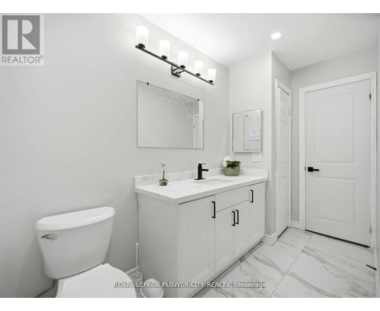 A white bathroom with a toilet, sink, and mirror.