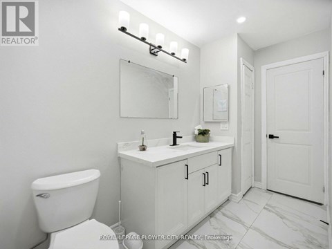 A white bathroom with a toilet, sink, and mirror.